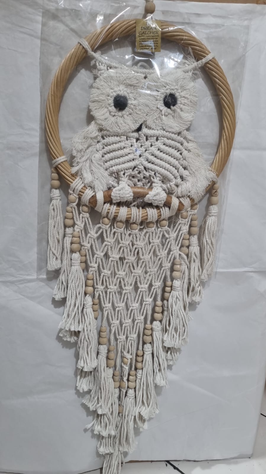 Handmade macrame dreamcatcher with soft fringe and rattan frame, in neutral tones for minimalist and rustic home decor.