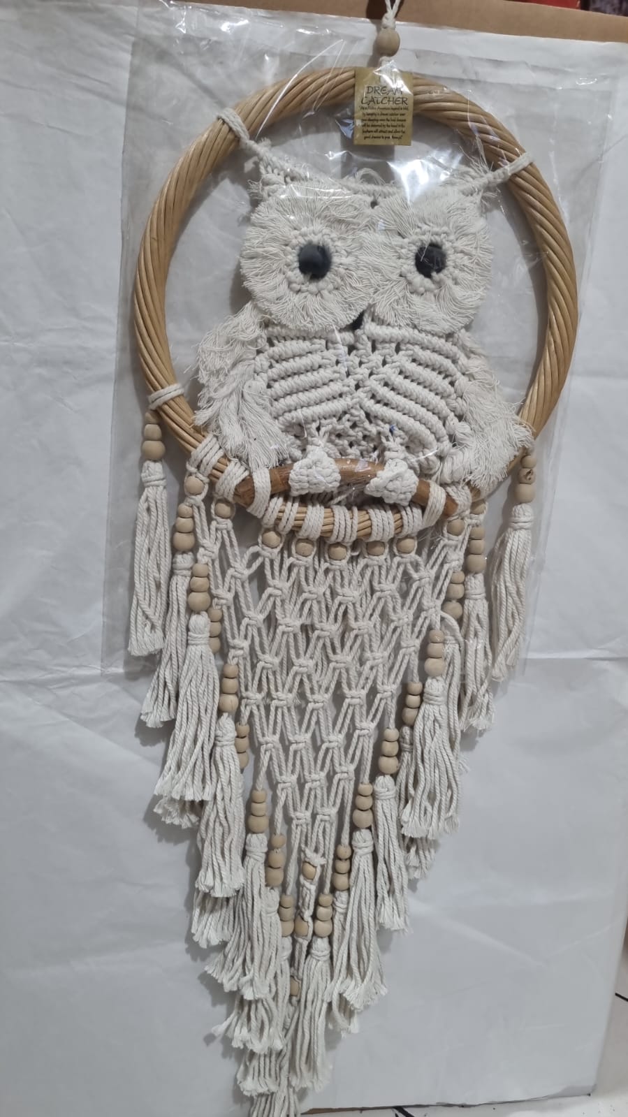 Handmade macrame dreamcatcher with soft fringe and rattan frame, in neutral tones for minimalist and rustic home decor.