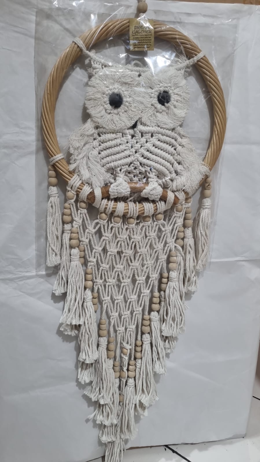 Handmade macrame dreamcatcher with soft fringe and rattan frame, in neutral tones for minimalist and rustic home decor.