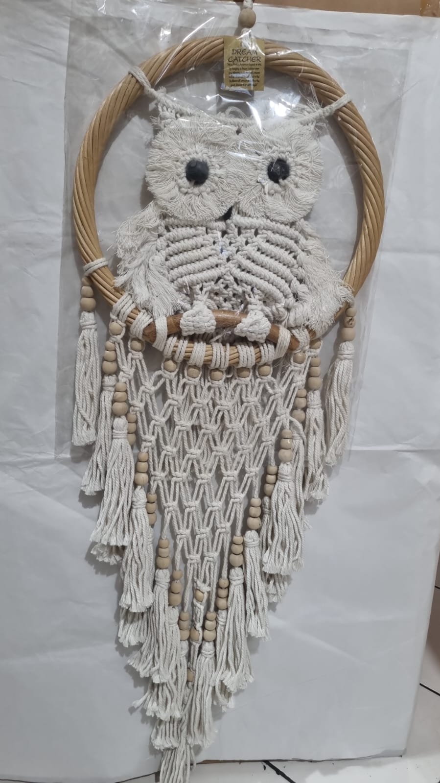 Handmade macrame dreamcatcher with soft fringe and rattan frame, in neutral tones for minimalist and rustic home decor.