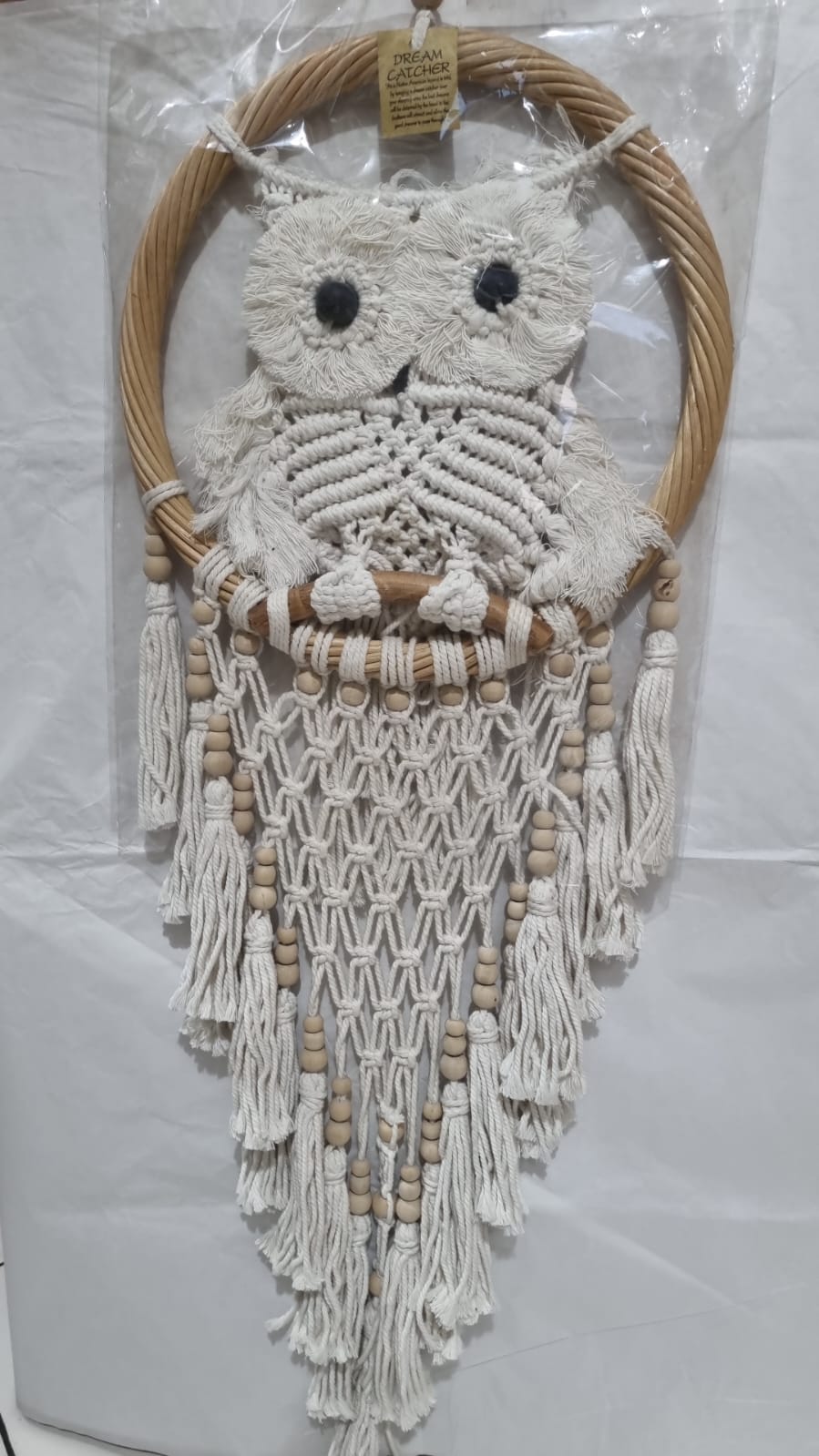 Handmade macrame dreamcatcher with soft fringe and rattan frame, in neutral tones for minimalist and rustic home decor.