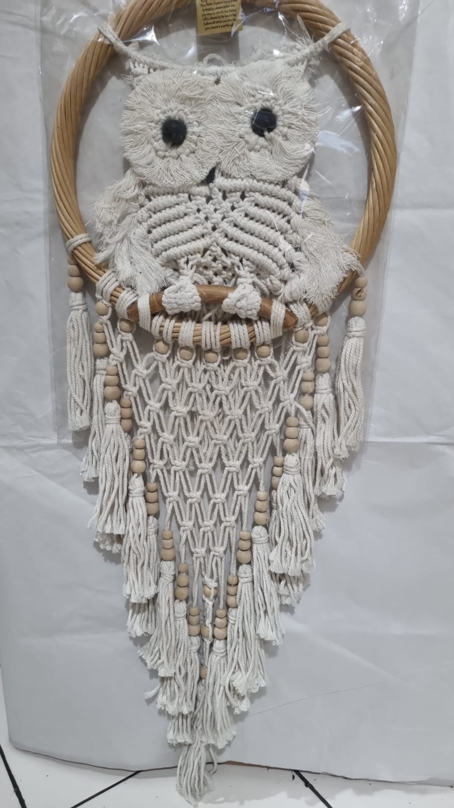 Handmade macrame dreamcatcher with soft fringe and rattan frame, in neutral tones for minimalist and rustic home decor.