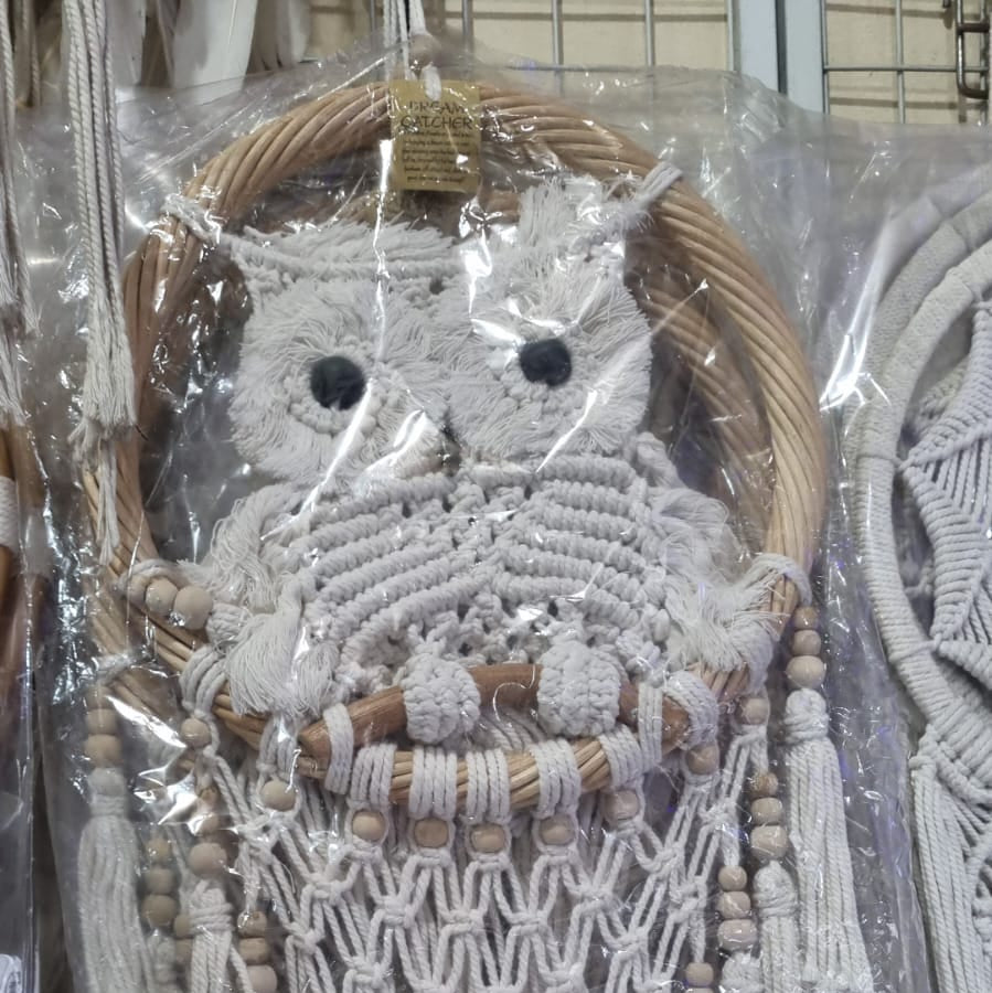 Handmade macrame dreamcatcher with soft fringe and rattan frame, in neutral tones for minimalist and rustic home decor.