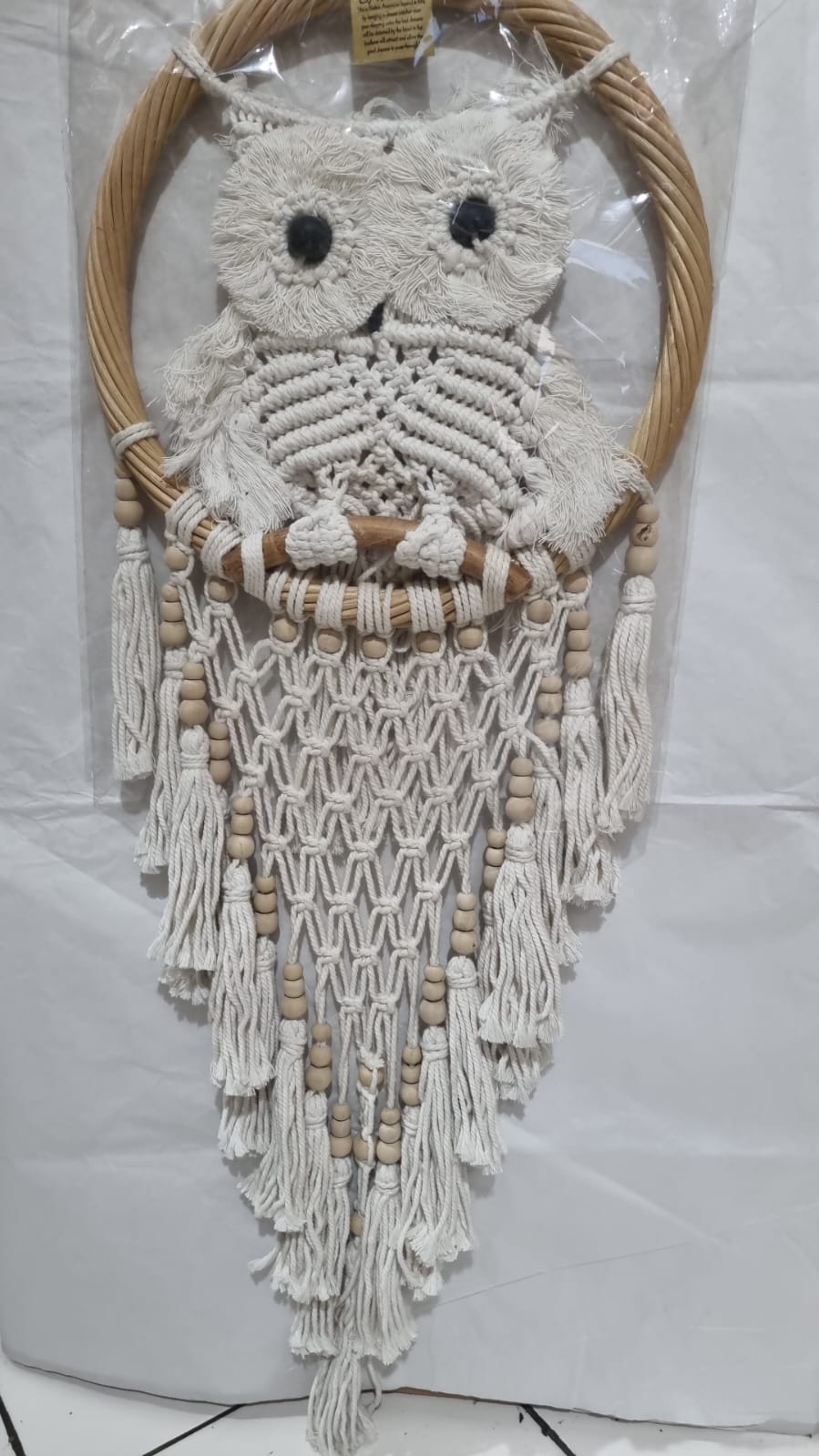 Handmade macrame dreamcatcher with soft fringe and rattan frame, in neutral tones for minimalist and rustic home decor.