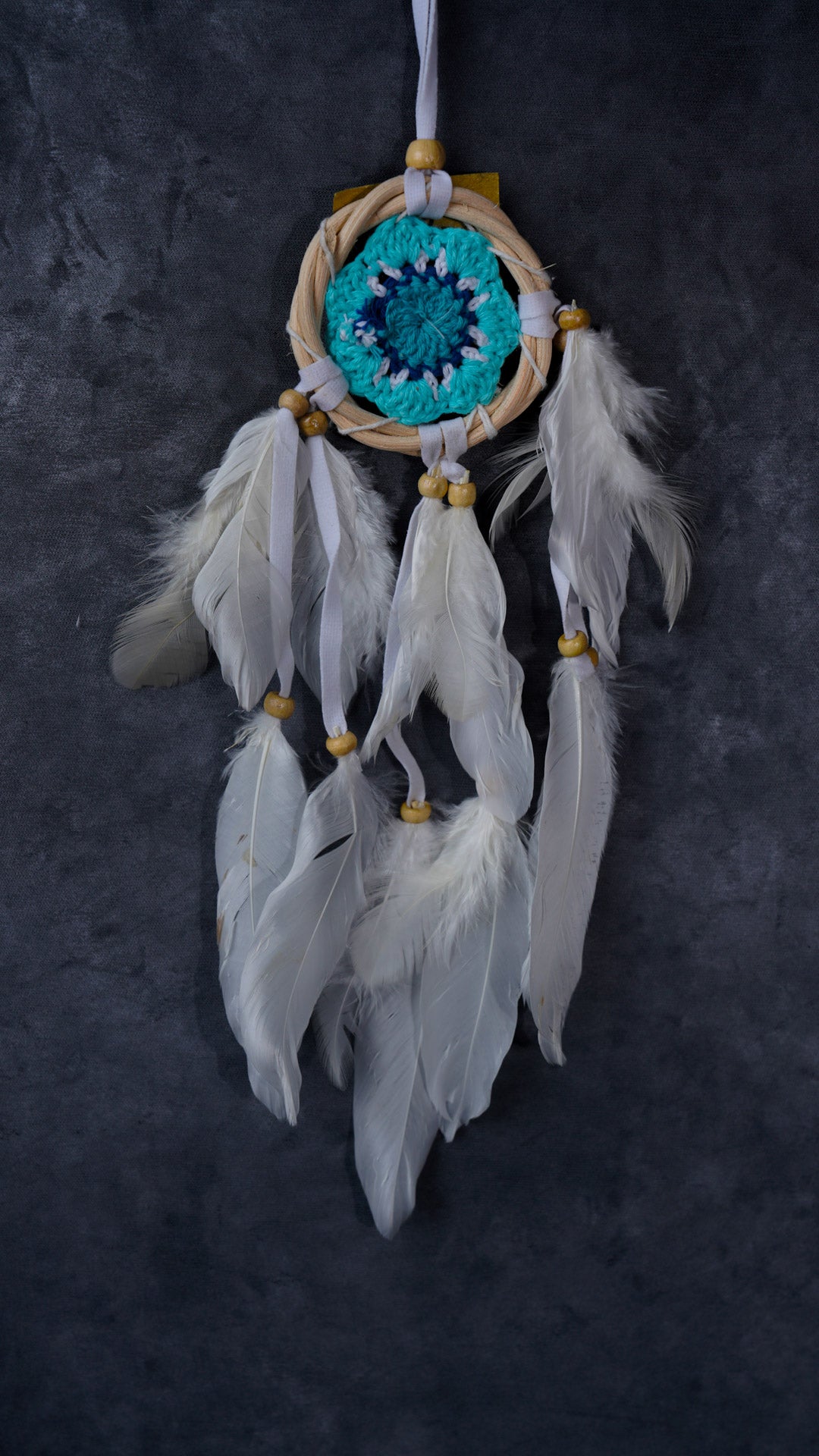 Hand-crocheted cotton mandala dream-catcher in rattan hoop with flowing white feathers and wood beads.