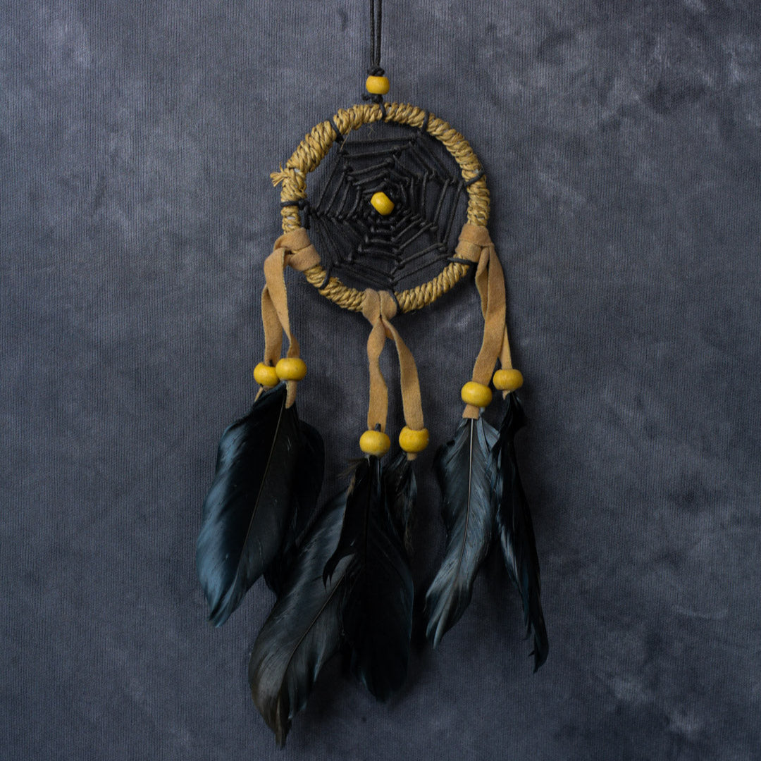 Hand-crafted cotton dreamcatcher with suede ties, wood beads and colorful feathers, sized for wall or car décor.
