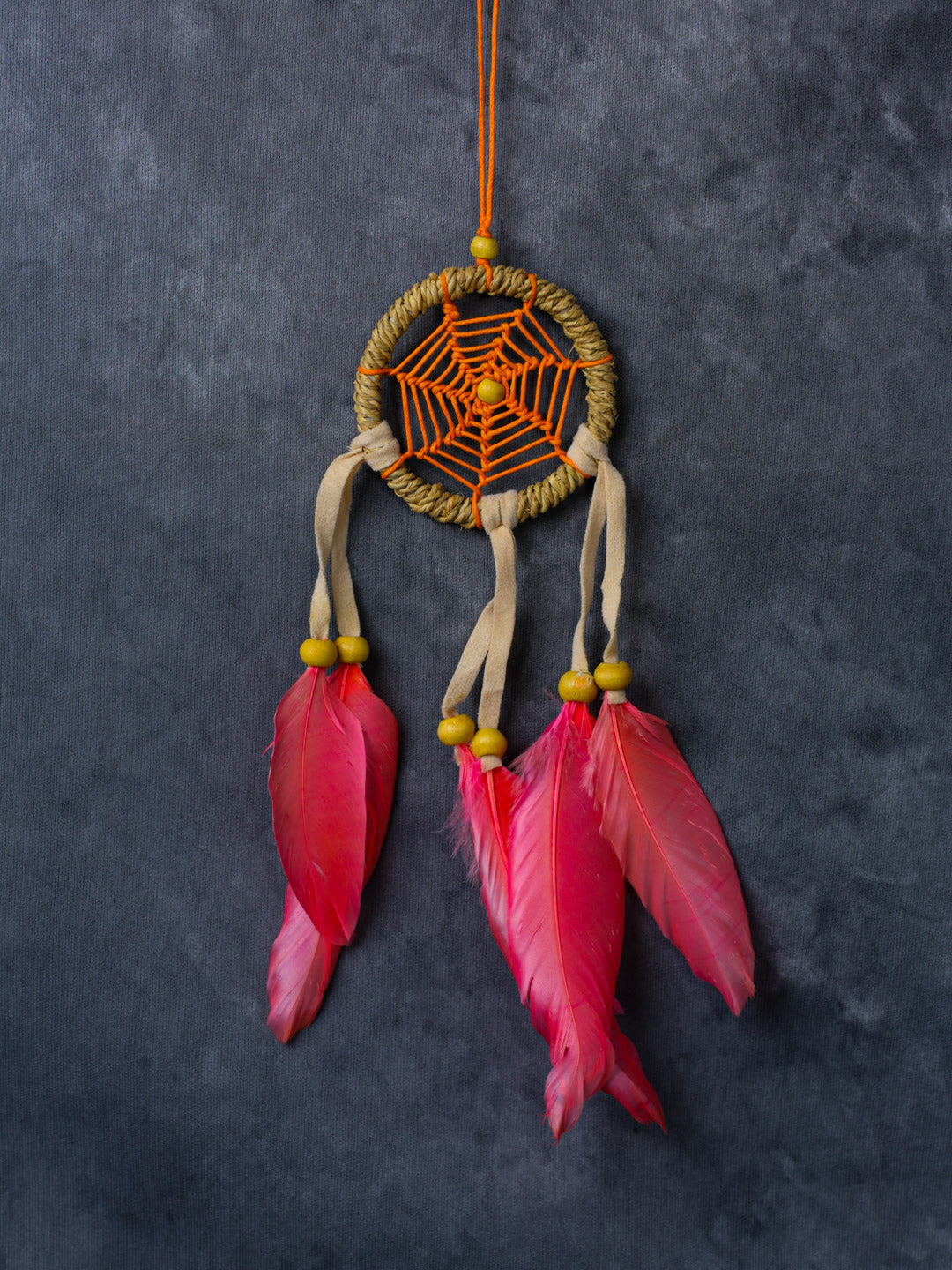 Hand-crafted cotton dreamcatcher with suede ties, wood beads and colorful feathers, sized for wall or car décor.