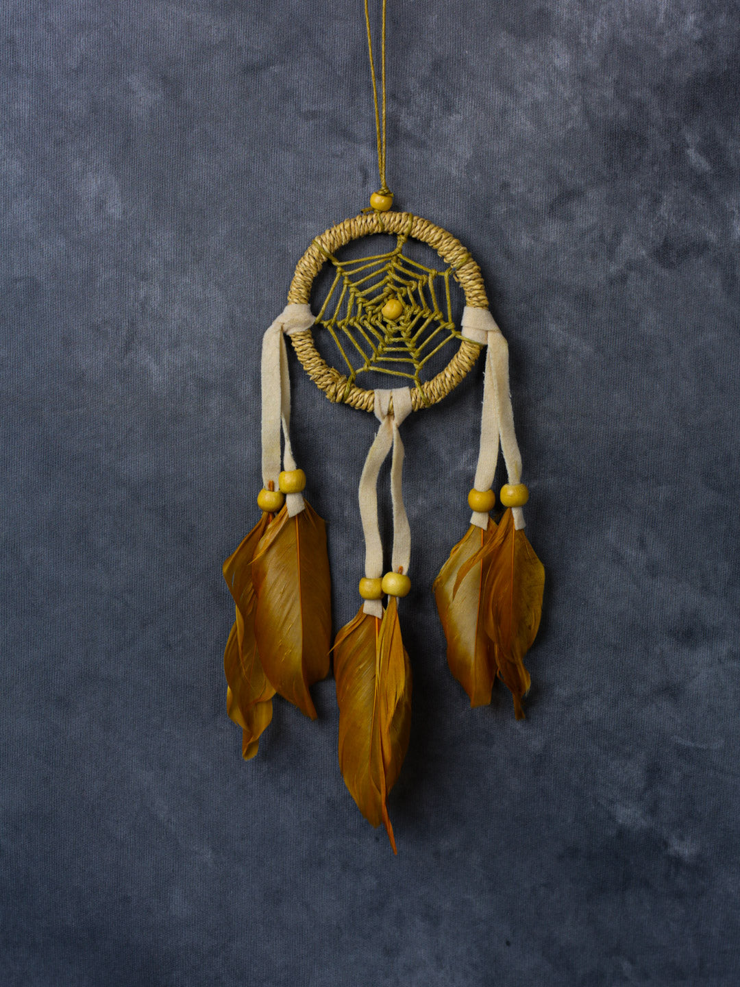 Hand-crafted cotton dreamcatcher with suede ties, wood beads and colorful feathers, sized for wall or car décor.
