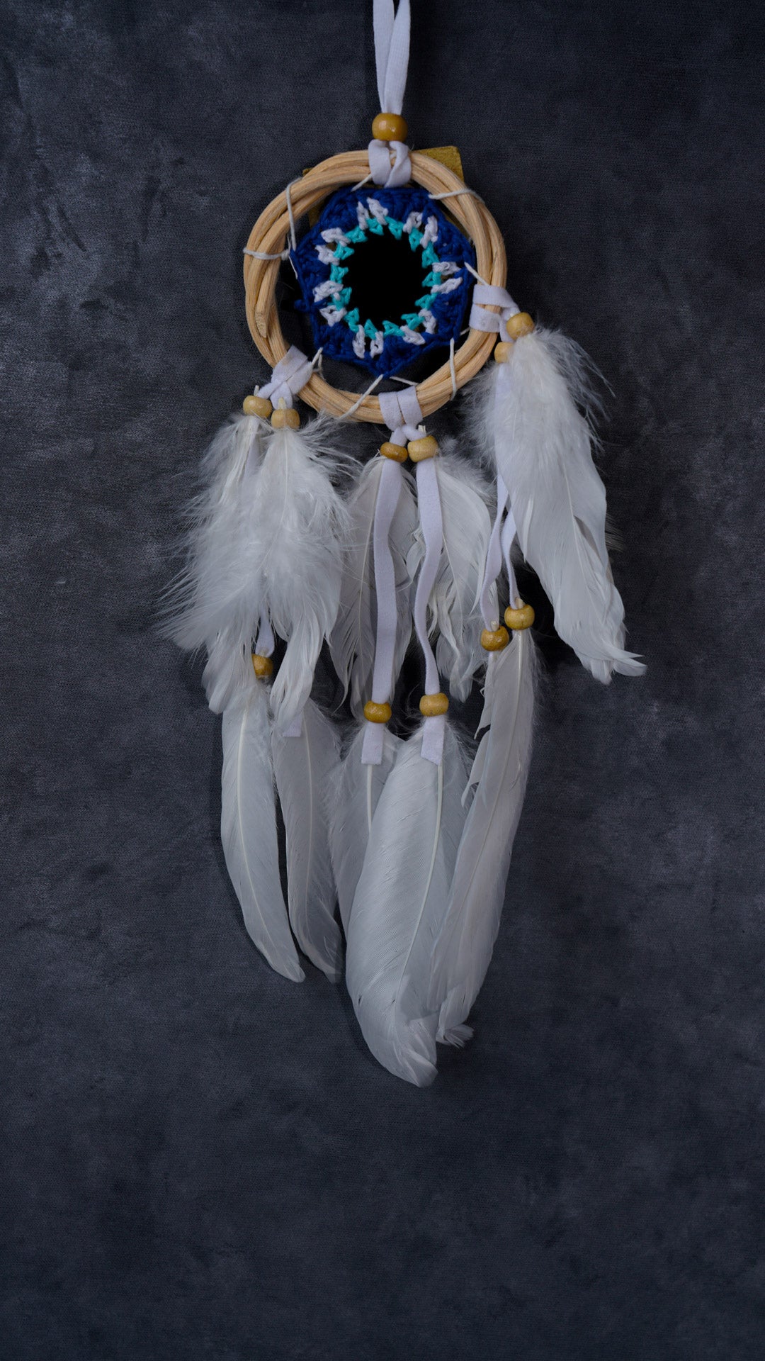 Hand-crocheted cotton mandala dream-catcher in rattan hoop with flowing white feathers and wood beads.