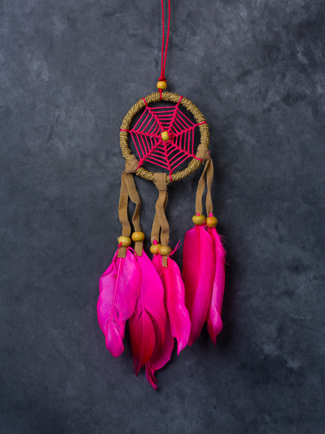 Hand-crafted cotton dreamcatcher with suede ties, wood beads and colorful feathers, sized for wall or car décor.