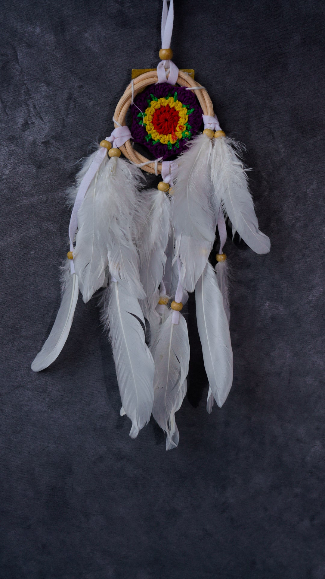 Hand-crocheted cotton mandala dream-catcher in rattan hoop with flowing white feathers and wood beads.