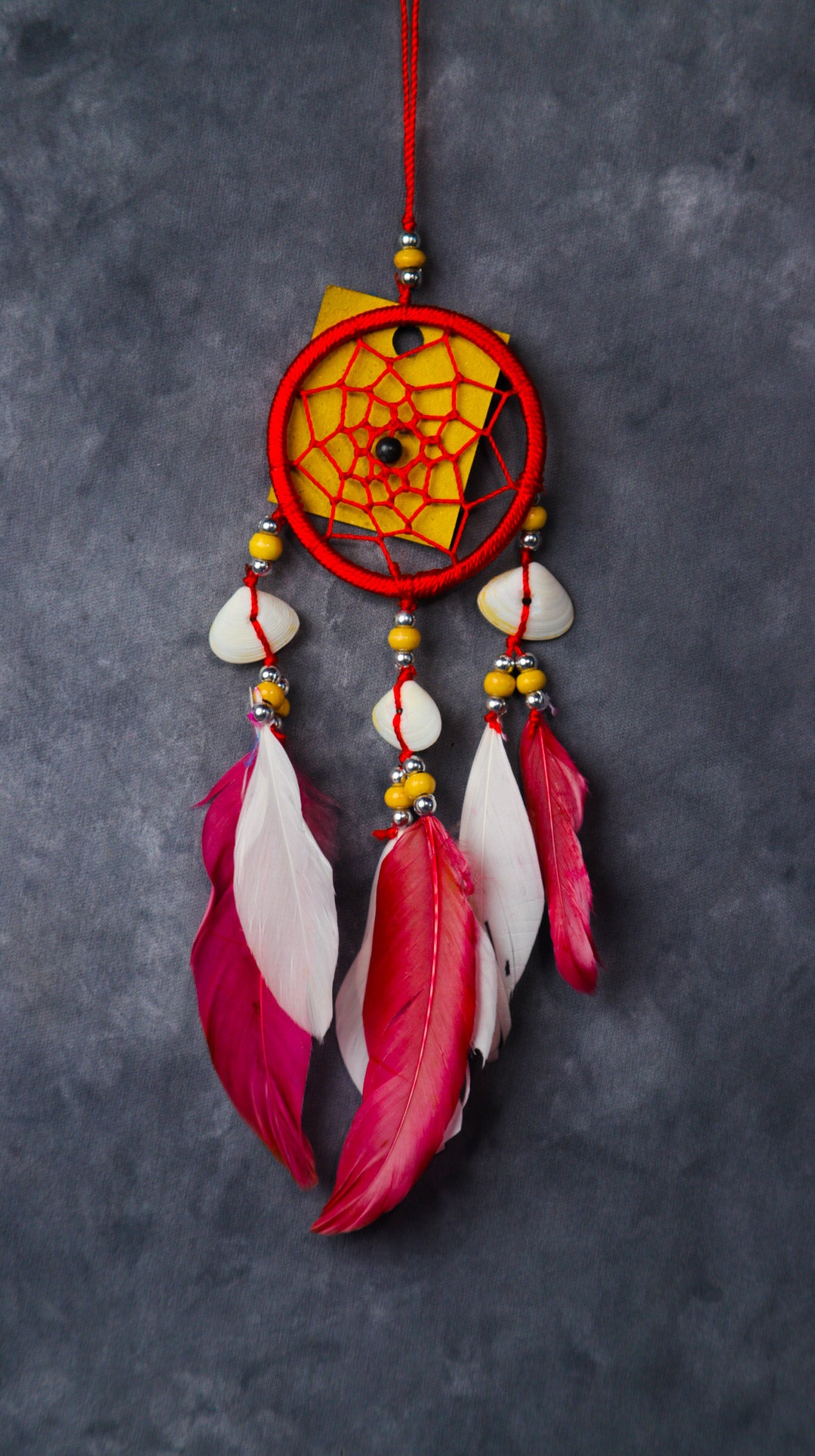 Close-up of a blue nylon dream-catcher with white and blue feathers hanging from a rear-view mirror.