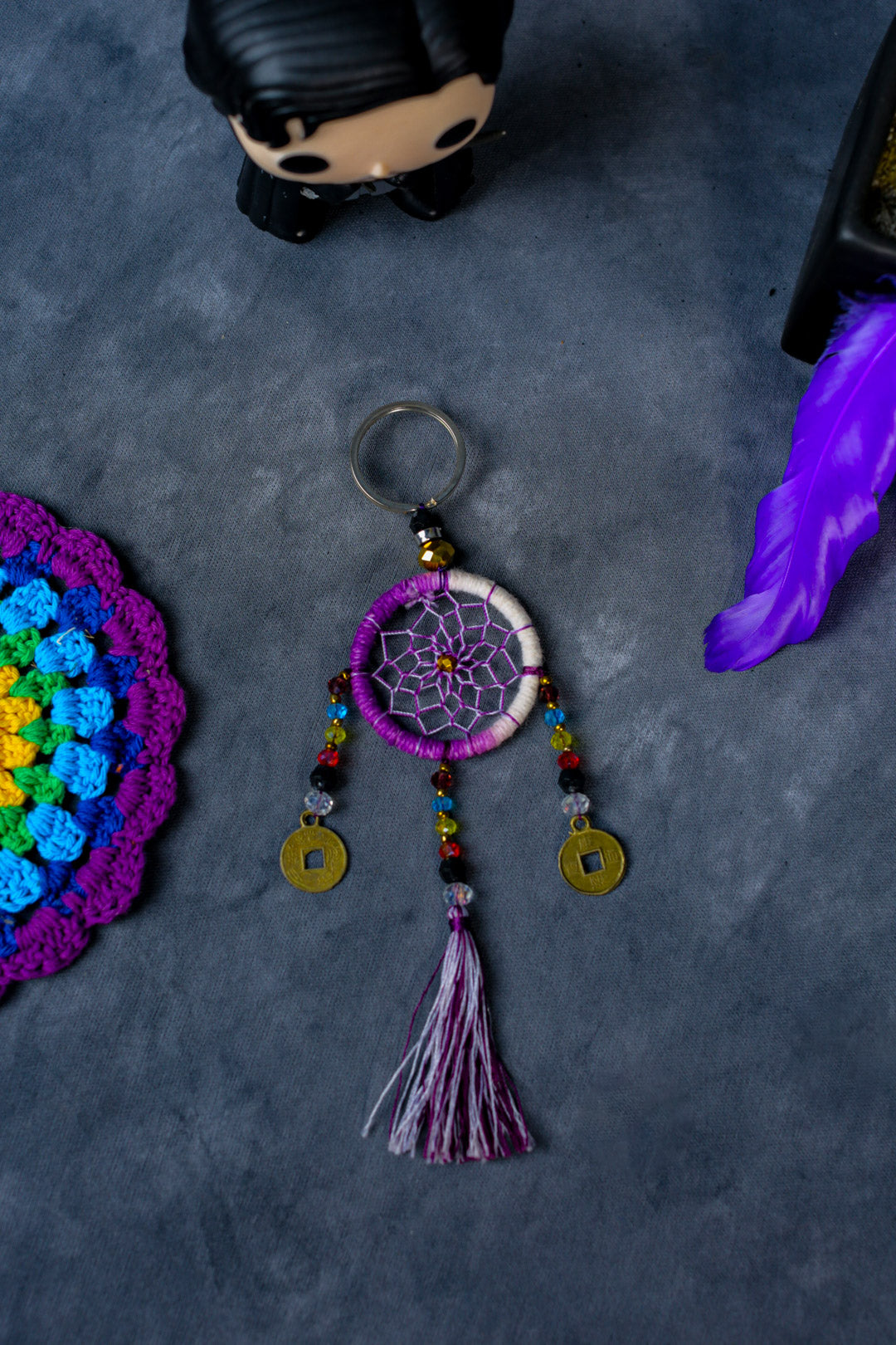 Hand-woven violet dreamcatcher keychain with tassel, beads, and lucky coins.