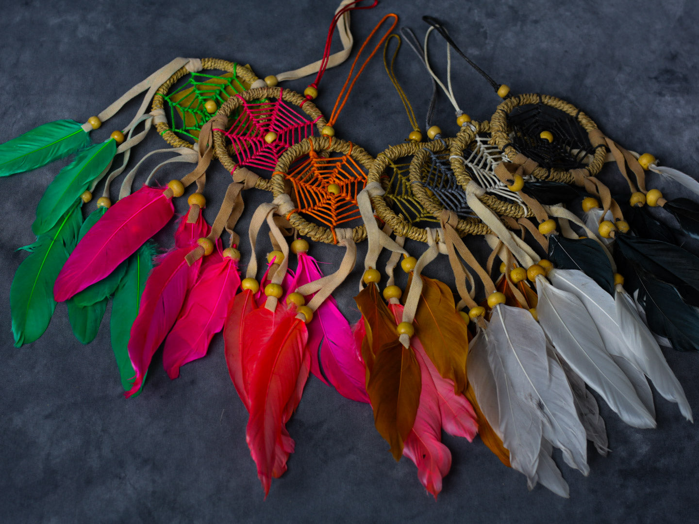 Hand-crafted cotton dreamcatcher with suede ties, wood beads and colorful feathers, sized for wall or car décor.