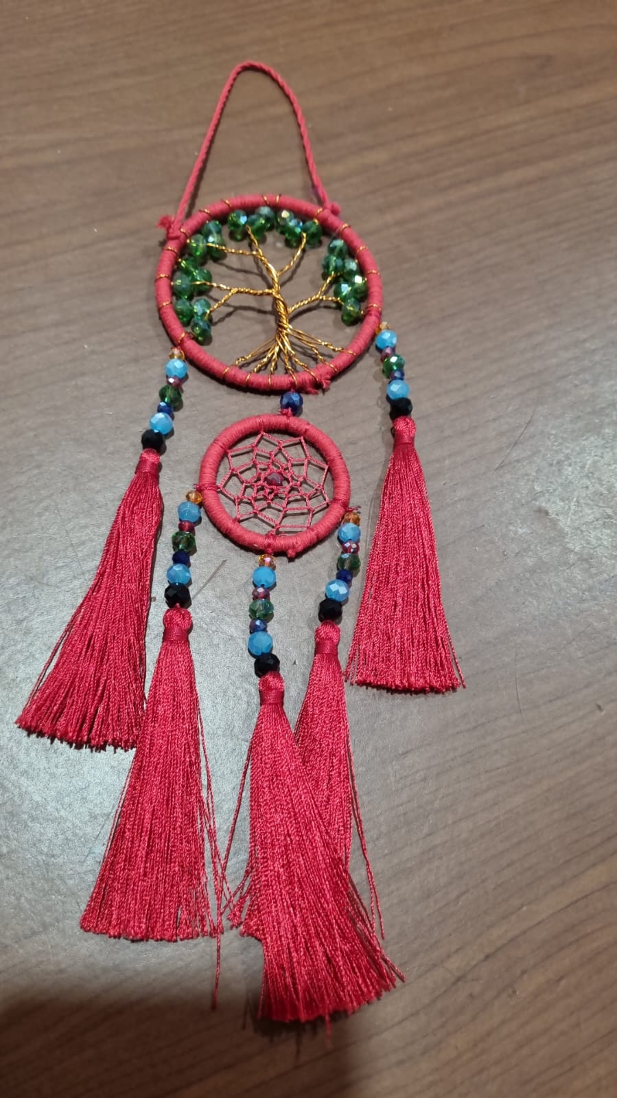 Artisan dreamcatcher with red tassels, tree of life wire design, and green crystal beads