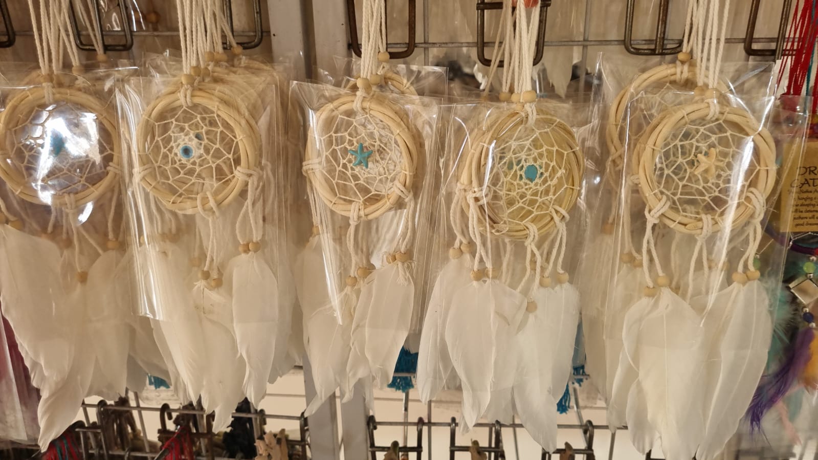 Small handmade rattan dreamcatcher 6 cm with white feathers, ideal for boho home or car decoration.