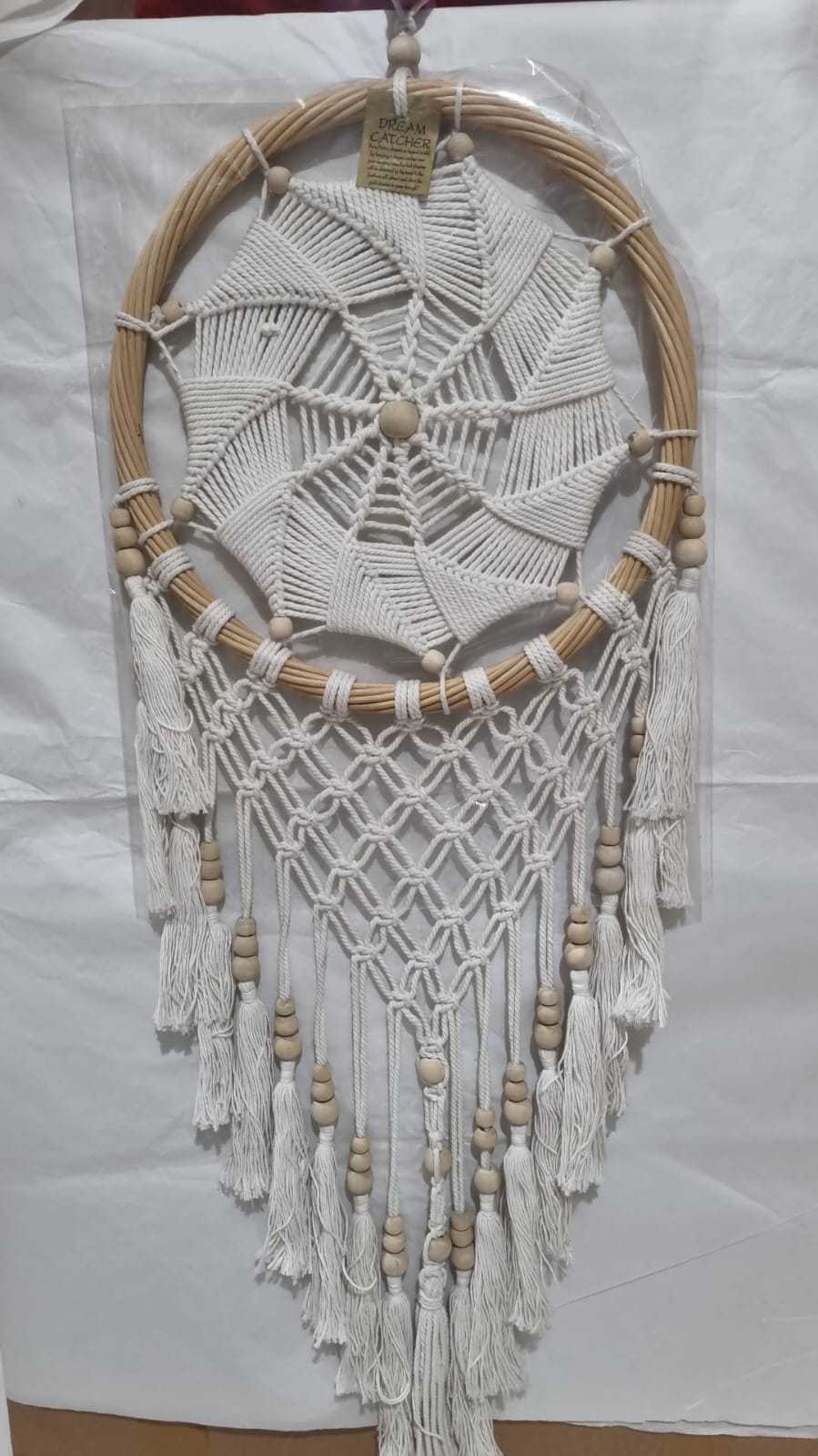 Rattan dreamcatcher with cotton spiral web and tassels, featuring wooden beads, perfect for boho wall décor or gifting.