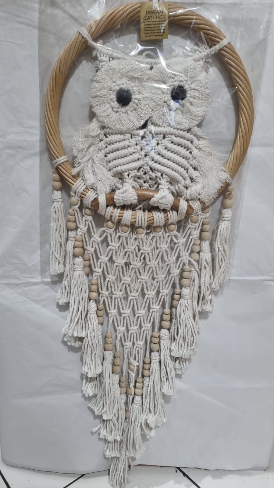 Handmade macrame dreamcatcher with soft fringe and rattan frame, in neutral tones for minimalist and rustic home decor.