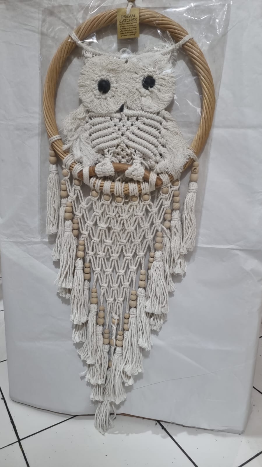 Handmade macrame dreamcatcher with soft fringe and rattan frame, in neutral tones for minimalist and rustic home decor.