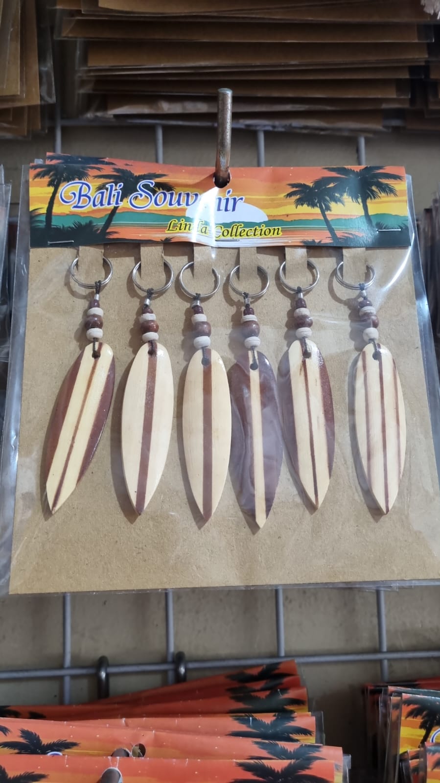 Resin surfboard keychain with shell accents, handmade souvenir keyring for bulk wholesale and surf shop gifts.
