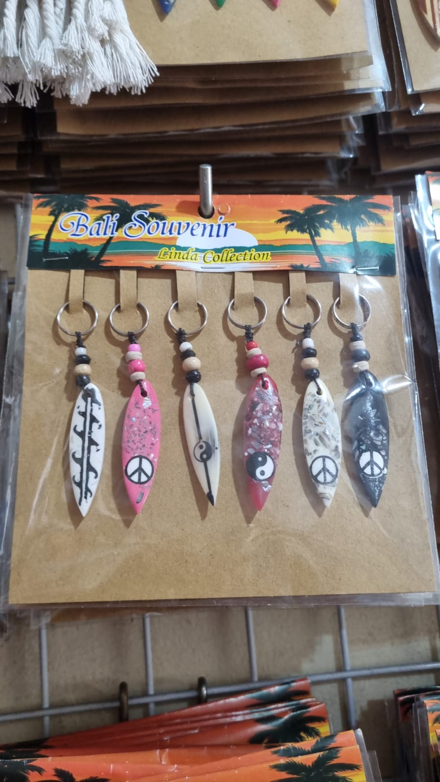Resin surfboard keychain with shell accents, handmade souvenir keyring for bulk wholesale and surf shop gifts.