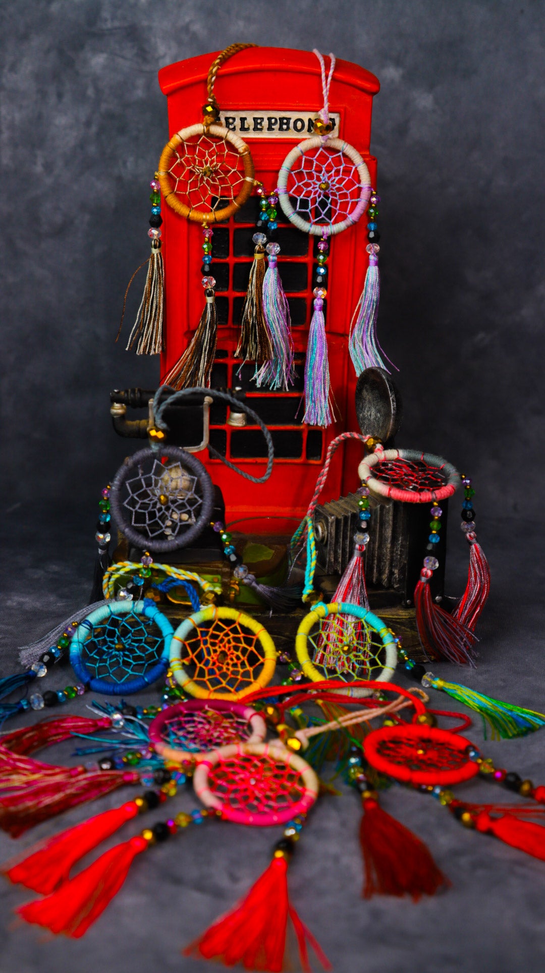 Mini dream-catcher tassel charm in rainbow tones hanging on a rear-view mirror.