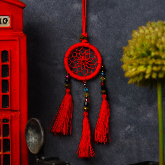 Mini dream-catcher tassel charm in rainbow tones hanging on a rear-view mirror.