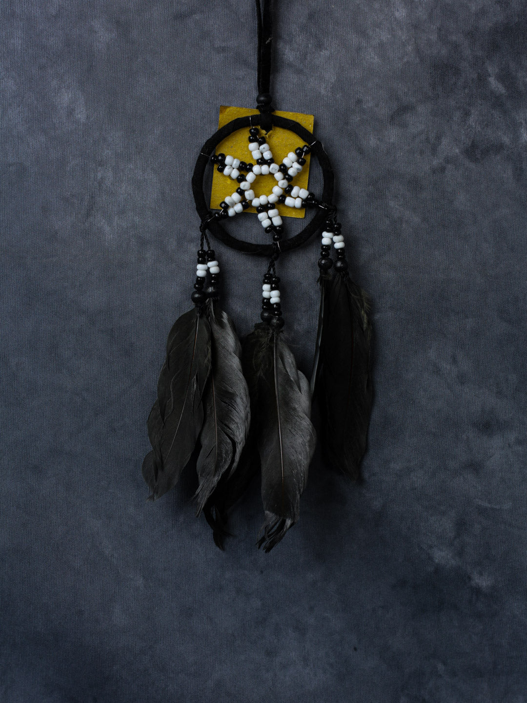 Black beaded star dreamcatcher with three feathers, hanging ribbon, and cotton hoop.