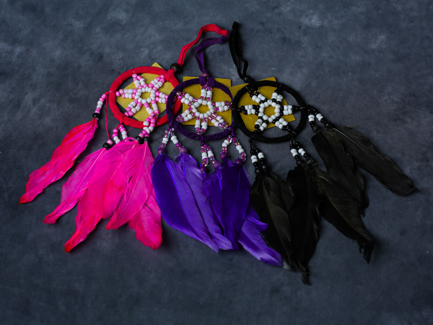 Purple, Black, Pink beaded star dreamcatcher with three feathers, hanging ribbon, and cotton hoop.