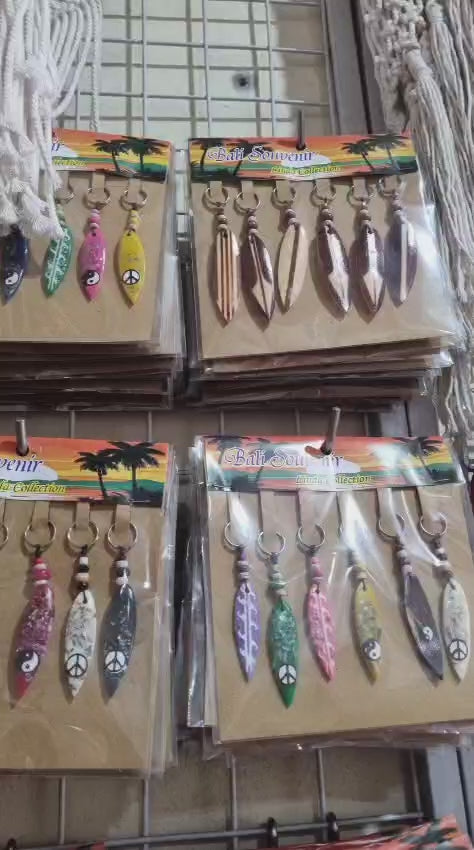 Resin surfboard keychain with shell accents, handmade souvenir keyring for bulk wholesale and surf shop gifts.