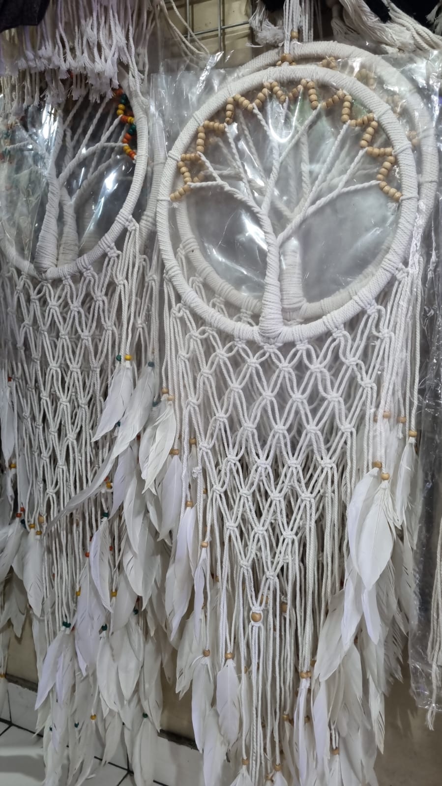 Macrame dreamcatcher in Tree of Life design, featuring wooden beads and white feathers, ideal for boho home decor or spiritual spaces.